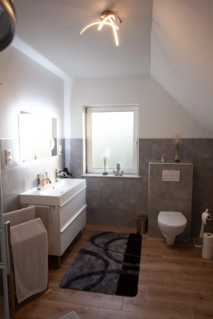 Modernes Badezimmer der Ferienwohnung Canhusen mit großer Dusche, Waschmaschine und Trockner