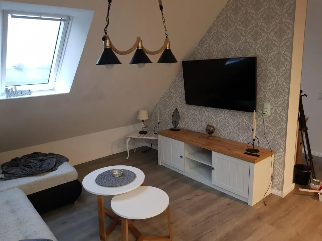 Offener Wohnbereich der Ferienwohnung Canhusen mit Schlafsofa und Smart-TV
